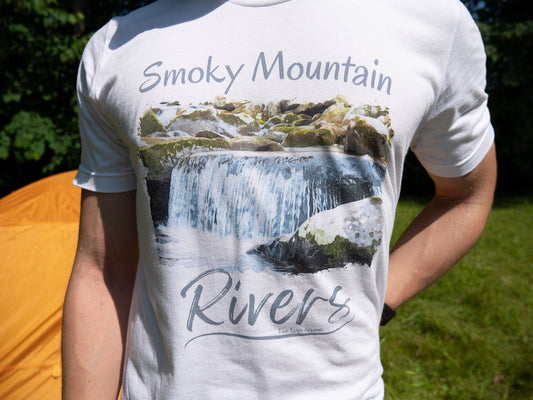 Smoky Mountain Rivers T-Shirt inspired by the Great Smoky Mountain National Park by East Ridge Apparel. Picture shows the front of the Smoky Mountain Rivers T_Shirt by East Ridge Apparel with a camping tent in the distant backdrop.